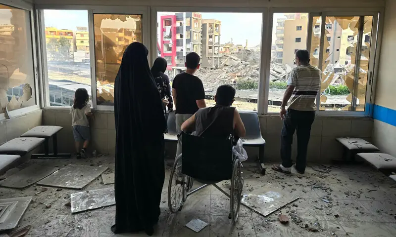  Tyre (Lebanon): People look through the damaged windows of the Jabal Amel hospital, which resumed operations on Tuesday after 39 staffers were injured following an Israeli strike a day earlier.&mdash;AFP 