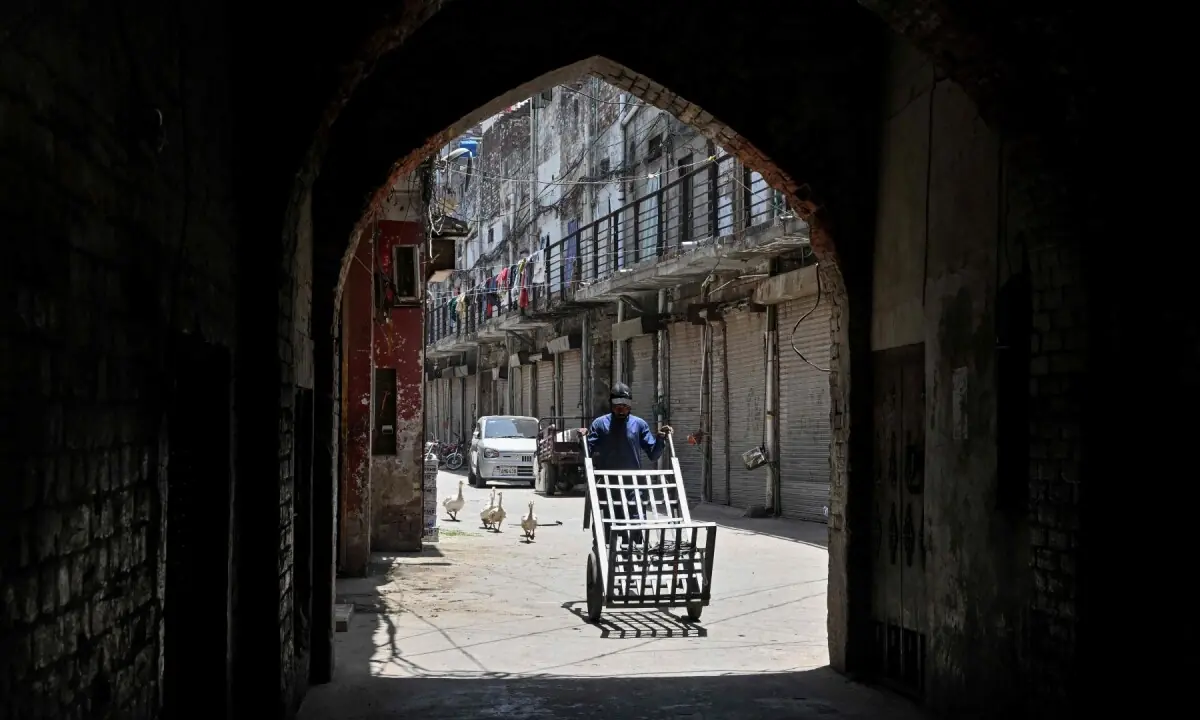 A worker pushes a cart along a street on a hot summer day in Lahore on June 9, 2026. —AFP