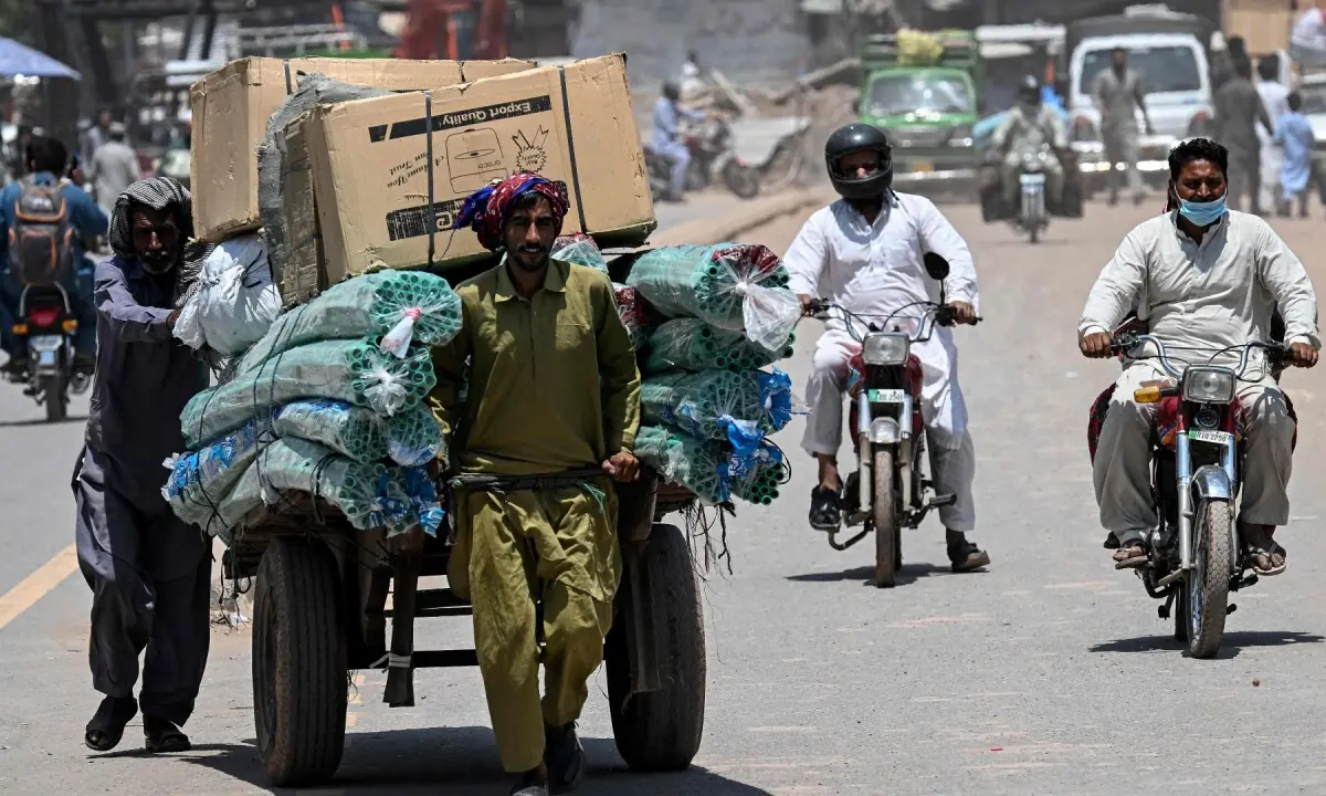 Labourers cover their heads with cloth as they push a loaded cart amid a heatwave in Rawalpindi on June 9, 2026. —AFP