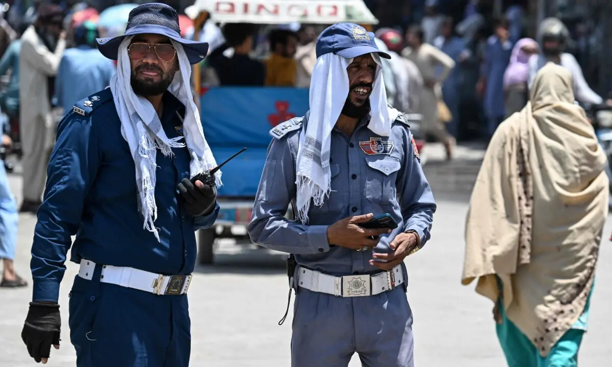 Traffic police personnel cover their heads with cloth as they stand at a road junction amid a heatwave in Rawalpindi on June 9, 2026. —AFP