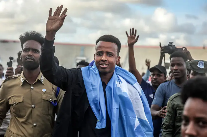 MOGADISHU: Somali international referee Omar Abdulkadir Artan waves to supporters while draped in the national flag as he is welcomed home ahead of a solidarity football match on Wednesday.—AFP