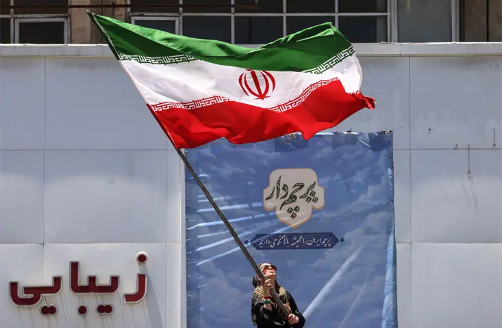 An Iranian woman waves a national flag at Tehran’s Valiasr Square, after the United States and Iran agreed on a peace deal to end the over 100-day war.—AFP