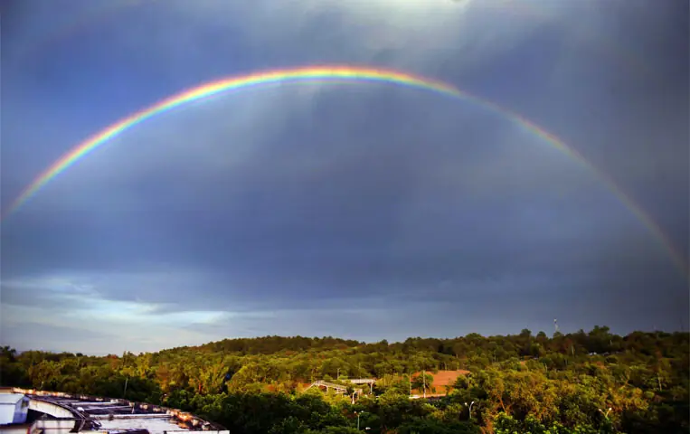 Youngsters play cricket on a road in Islamabad’s G-6 sector during rain on Sunday. The other picture shows a rainbow that broke out over the federal capital after the downpour. — Photos by Mohammad Asim