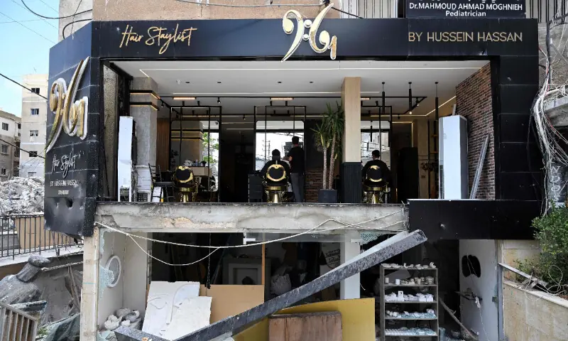  A hairdresser gives haircuts to his clients at his saloon damaged during previous the Israeli military strikes on the southern Lebanese coastal city of Tyre on June 23, 2026. &mdash; AFP 