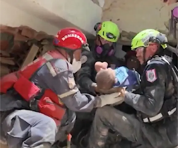  RESCUE workers carry a baby rescued from the rubble in La Guaira.&mdash;Reuters  