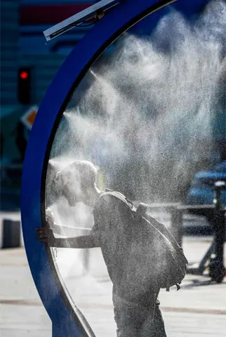  A man cools off while walking through a water sprayer installed in central Bucharest on Sunday.&mdash;AFP  