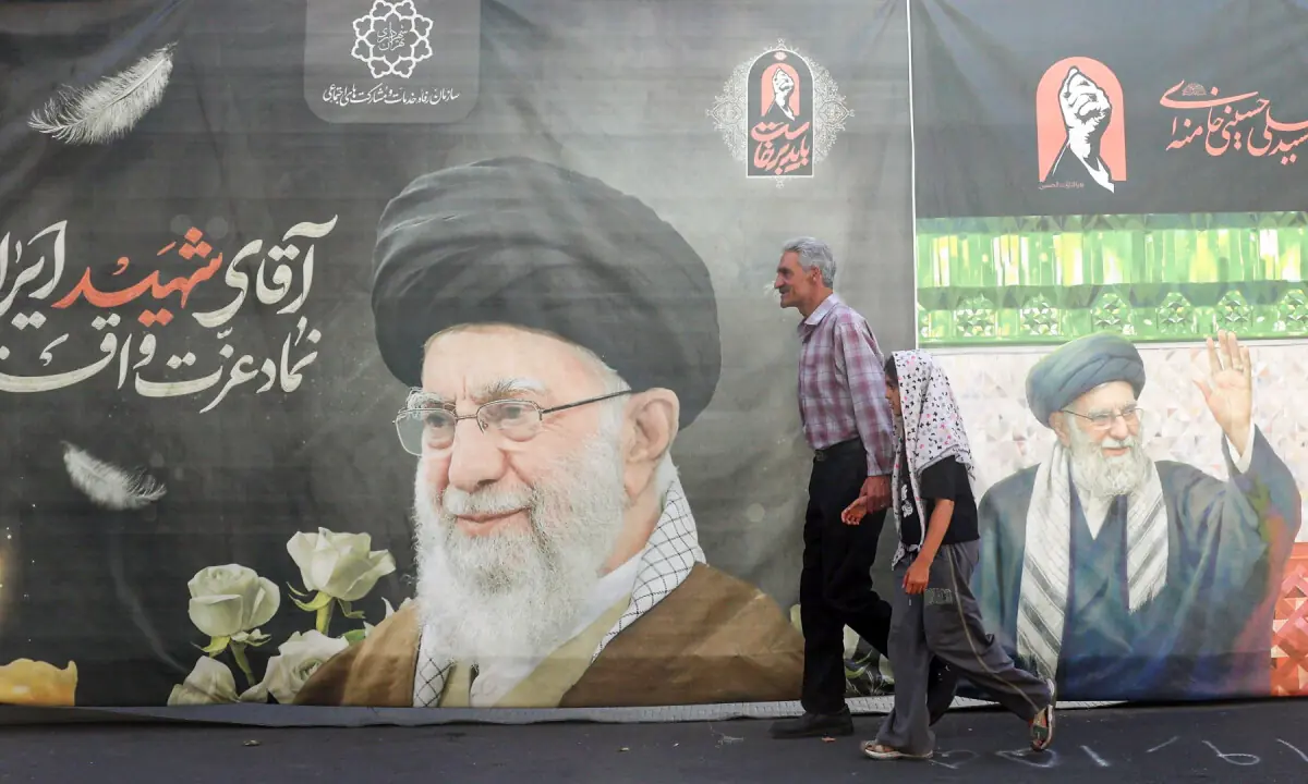 Iranians walk past a billboard bearing a picture of Iran’s assassinated supreme leader Ali Khamenei ahead of his funeral in Tehran on July 3, 2026. — AFP