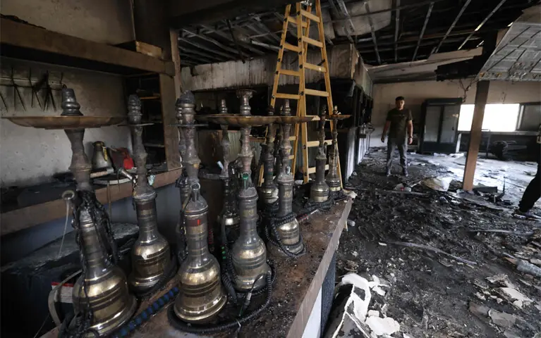 NABLUS: A Palestinian man inspects the aftermath at his restaurant after it was burned down by Israeli settlers in the occupied West Bank on Sunday.—AFP