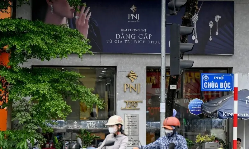 People ride motorbikes past a Phu Nhuan Jewelry (PNJ) store in Hanoi on July 15, 2026. —AFP