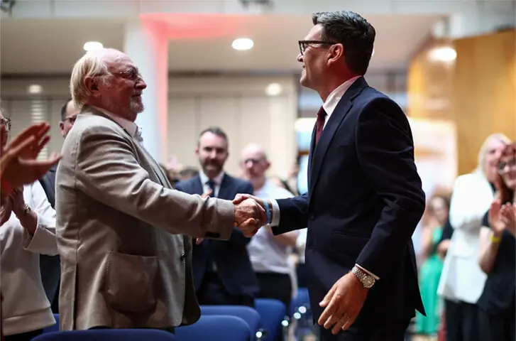 Andy Burnham (right) shakes hands with former Labour Party leader Neil Kinnock.—AFP