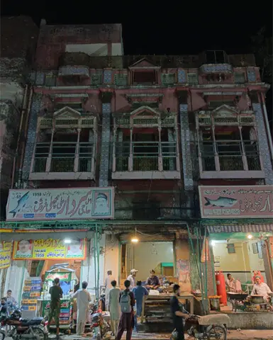 A handful of customers at a famous fish shop in Gawalmandi, with the beautiful façade of the structure above it in need of restoration | Photo by the writer