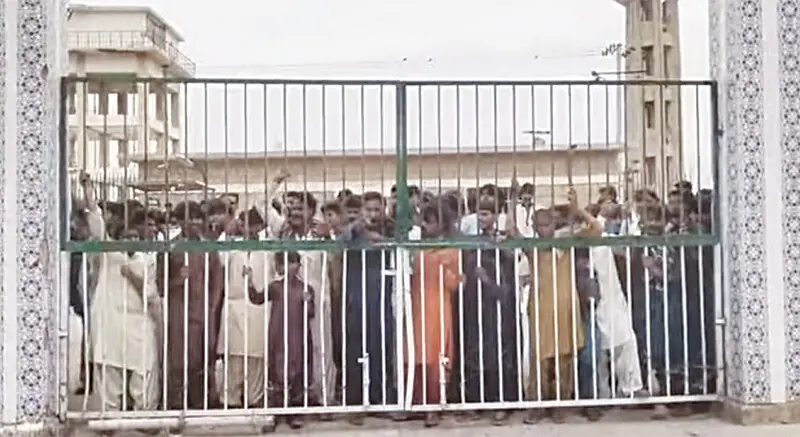 PROTESTING workers gather outside the closed gate of the STDC office at Keenjhar in Thatta district before storming their way into it.—Dawn