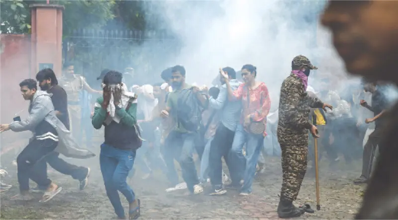 Supporters of the Cockroach Janta Party disperse after police fired tear gas shells at the protesters.—AFP