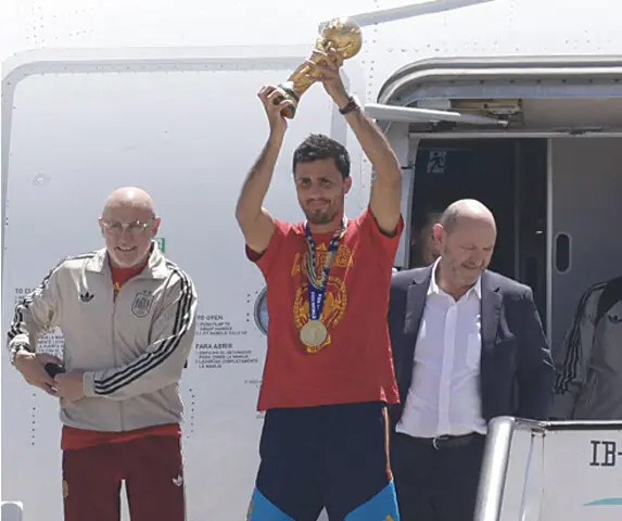 SPAIN coach Luis de la Fuente (L) smiles as captain Rodri holds the World Cup trophy upon their arrival at Madrid Barajas’ airport on Monday.—AFP