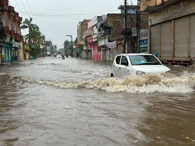  GUJRAT: A car drives through knee-deep rainwater that submerged Jinnah Road in the city. &mdash; Dawn 