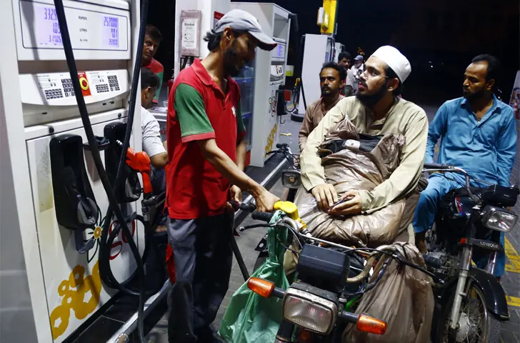  A MOTORCYCLIST hangs on to his shopping as a pump worker fills his tank. Motorists flocked to filling stations on Tuesday night after talks between the government and pump owners collapsed.&mdash;Shakil Adil / White Star 