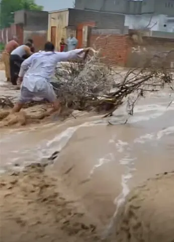 Residents of Dilawar village make frantic efforts to save their homes from flash floods. Locals say a section of the Dual Carriageway lacks proper drainage to divert torrents running down the Salt Range hills in Pind Dadan Khan. — Dawn