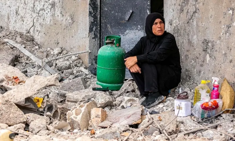 A woman sits next to a cooking gas canister by the rubble of her destroyed house in the village of Zawtar al-Gharbiyeh in southern Lebanon on July 26, 2026. &mdash;AFP