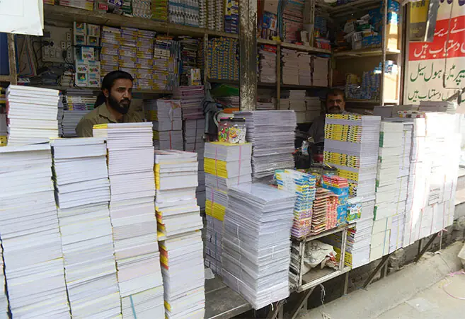 Piles of notebooks are stacked in a shop where customers buy them at wholesale prices.