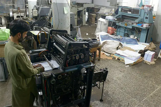 A worker operates a printing press in the backyard of the main bazaar.