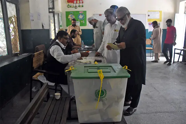  RAWALPINDI: People receive ballot papers from election officials as they wait to cast their votes at a polling station in Millat Colony, during the second phase of elections to the AJK Legislative Assembly.&mdash;Online 