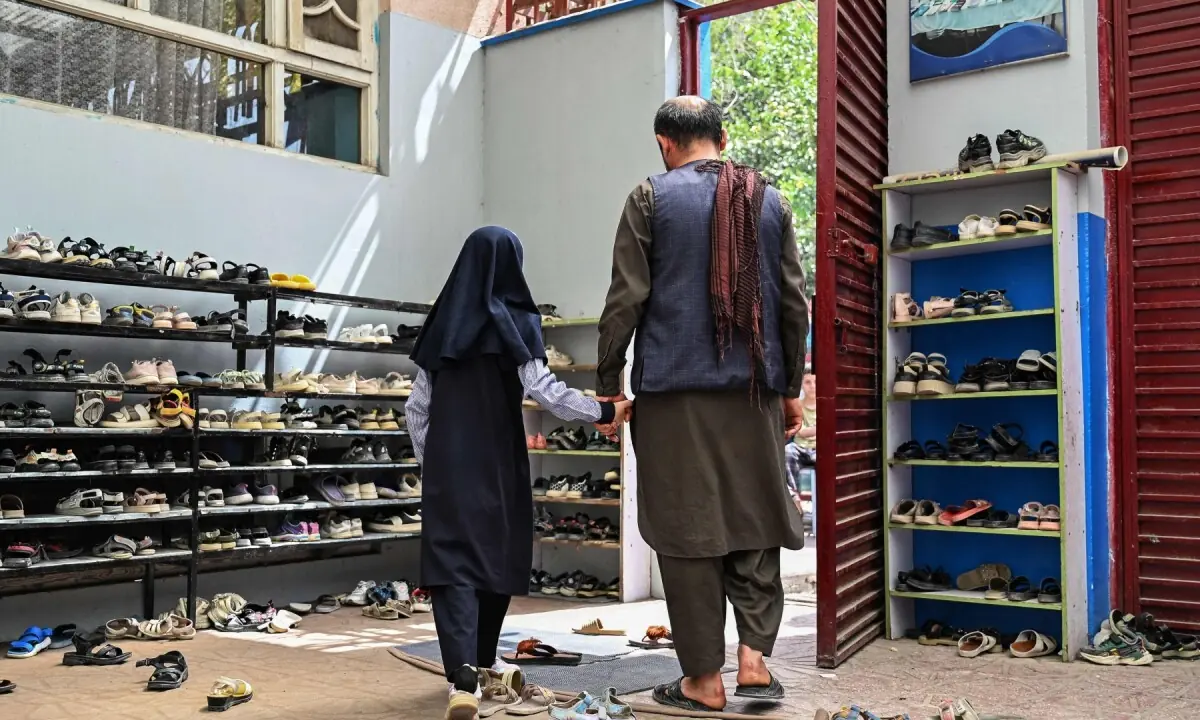 This photograph taken on July 21, 2026 shows an Afghan schoolgirl holding her father’s hand leaving after taking a midterm exam at a primary school in Kabul. —AFP/File
