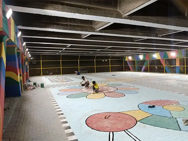 Artists paint board-game designs on the ground at the sports facility.—Photo by the writer