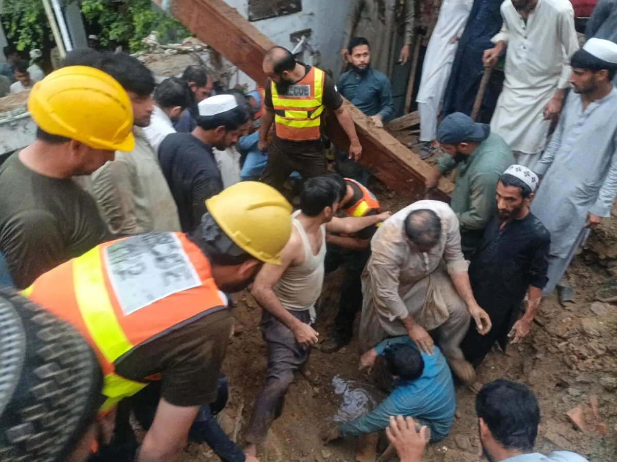 Rescue workers and locals recover an injured person from the debris of a collapsed house in Swabi on Thursday. — Photo by Muqaddam Khan