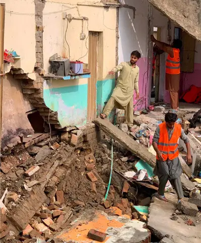 A resident and rescue workers collect household items from a house that collapsed in Swabi on Friday. — Dawn