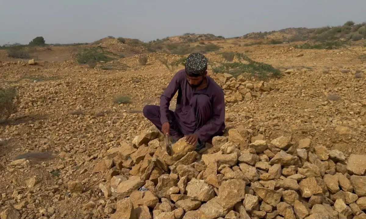  Sultan Bugti breaks stones on a hillside in Gadap Town. 