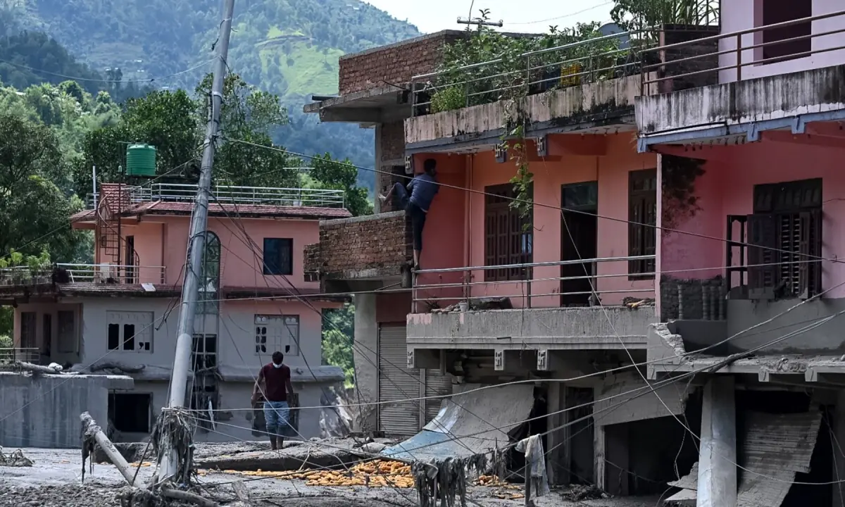 A man climbs up to salvage belongings from his house lying deluged in sludge after flash floods in the Devighat area in Nepal&rsquo;s Nuwakot district on August 27, 2026. &mdash;AFP