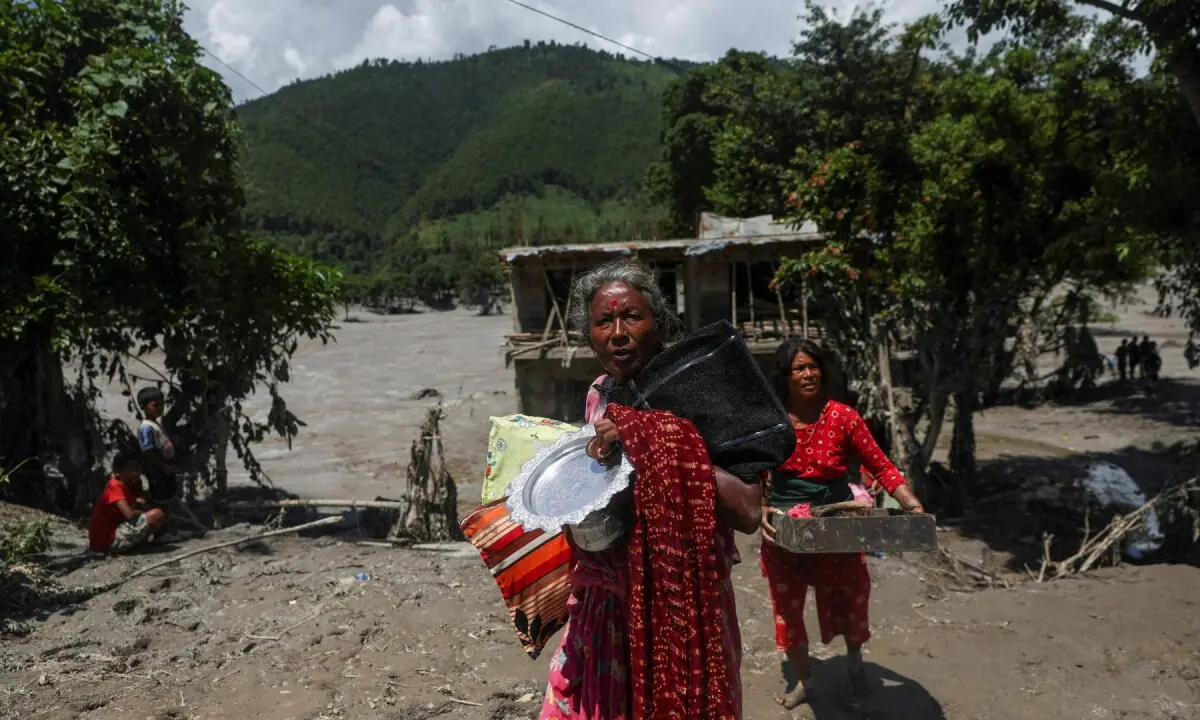 Women carry belongings from their damaged homes after a flash flood and a mudslide, in Galchhi, Nepal on August 27, 2026. &mdash;Reuters