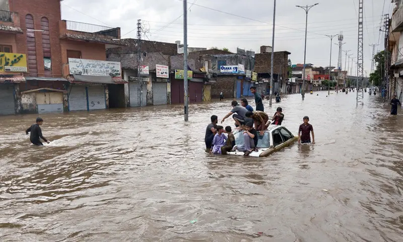  Children sit on the roof of a vehicle stranded in floodwater in Rahimabad. &mdash; Photos by Mohammad Asim 
