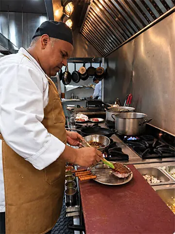The chef preparing food in the open kitchen on the upper floor