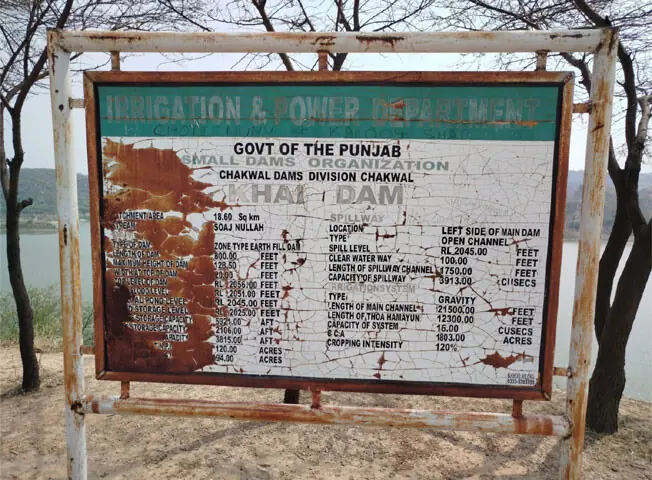 A signboard displaying the salient features of Khai Dam in Chakwal lies rusted.