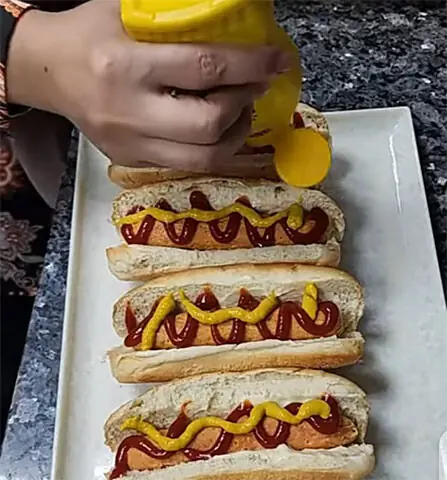 A hot dog is a cooked sausage served inside a partially sliced bread roll or bun, usually topped with ketchup and mustard