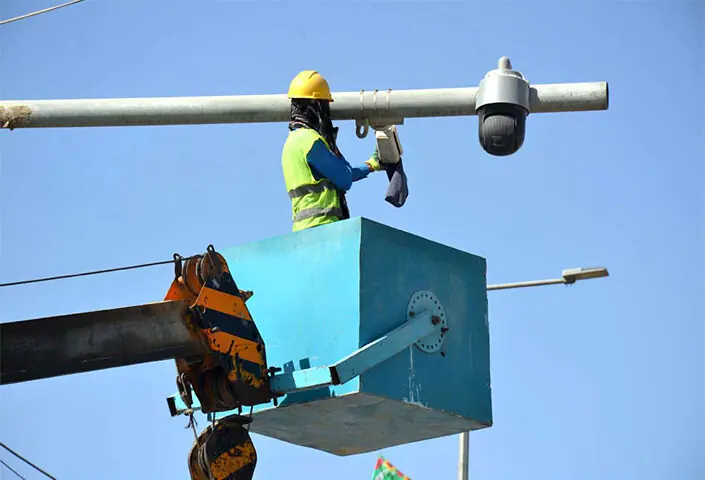 A worker cleans surveillance cameras and solar panels installed under the Safe City project along Joint Road in Quetta.—APP