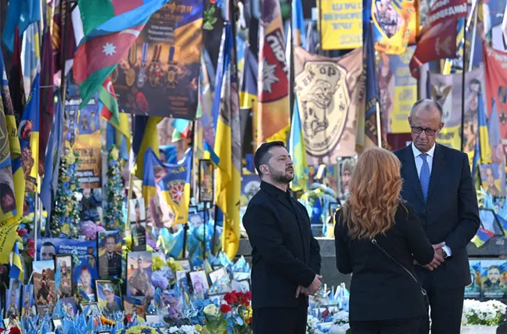 UKRAINE’S President Volodymyr Zelensky and German Chancellor Friedrich Merz stand next to a makeshift memorial for Ukrainian and foreign soldiers on Independence Square in Kyiv.—AFP
