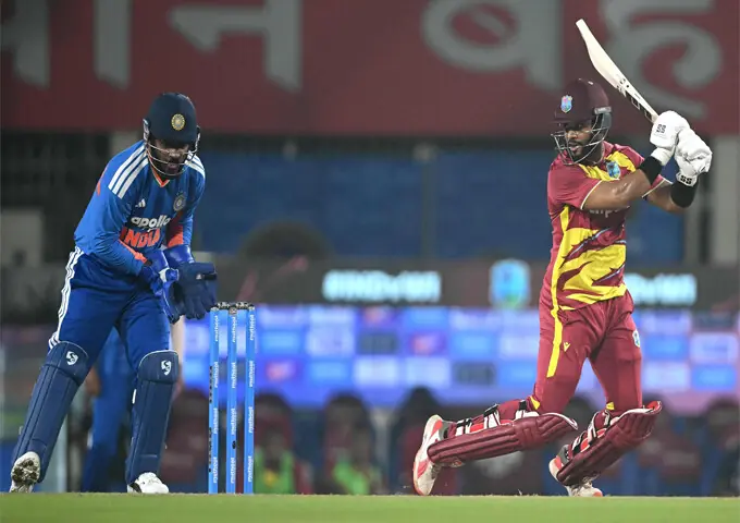 WEST INDIES captain Shai Hope plays a shot as Indian wicket-keeper Sanju Samson watches during the second T20 International at the JSCA International Stadium Complex on Friday.—AFP