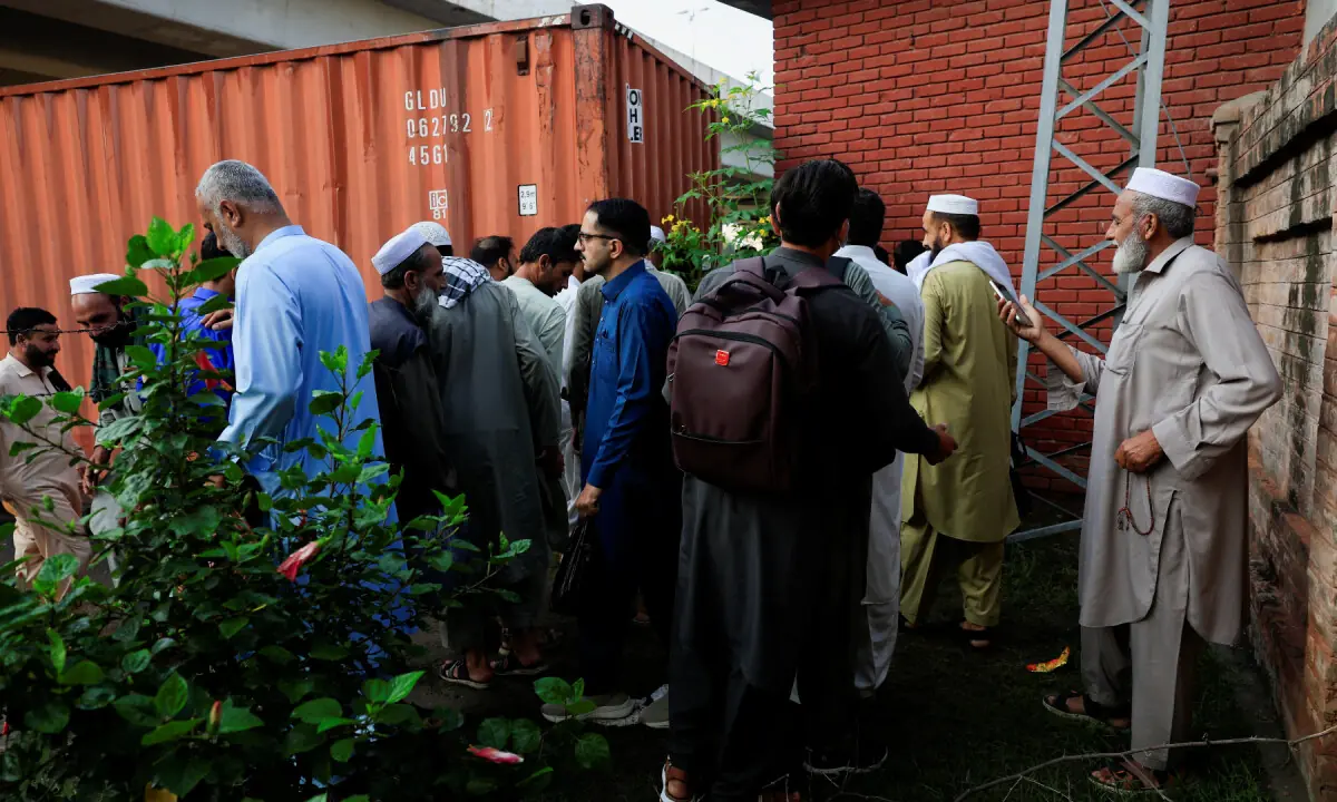 People navigate past shipping containers used to block access to Peshawar&rsquo;s Red Zone a day after the government imposed a state of emergency in KP on October 12, 2026. &mdash; Reuters