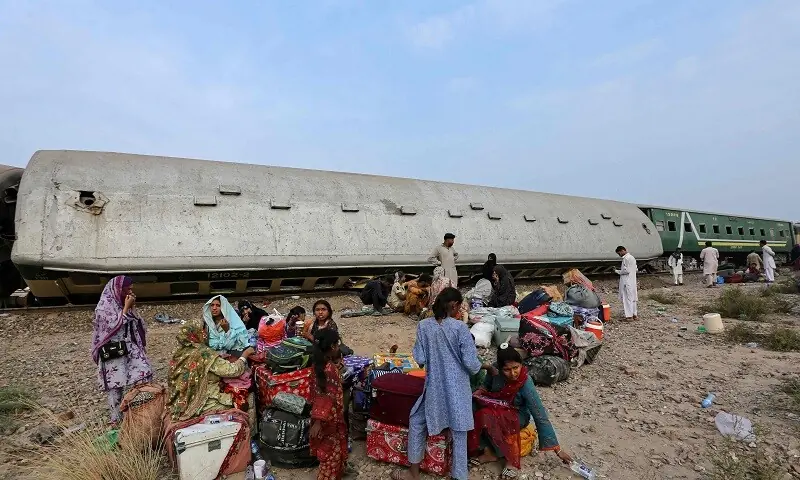 Passengers sit with their belongings next to derailed coaches of the passenger train Rehman Baba Express on the outskirts of Multan on October 13, 2026. &mdash; AFP