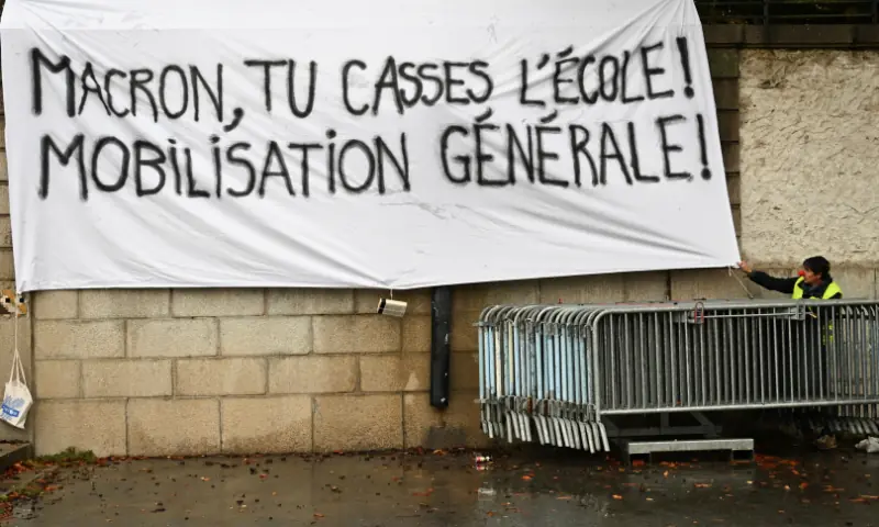This photograph shows a banner which reads as ’Macron, You break scholl! — AFP