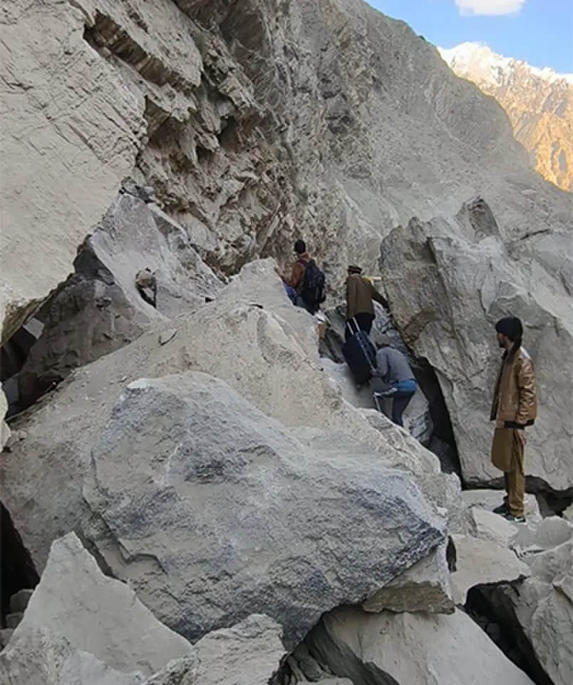 Passengers cross a road blocked by boulders in the Shangus area of Skardu’s Roundu Valley.—Dawn