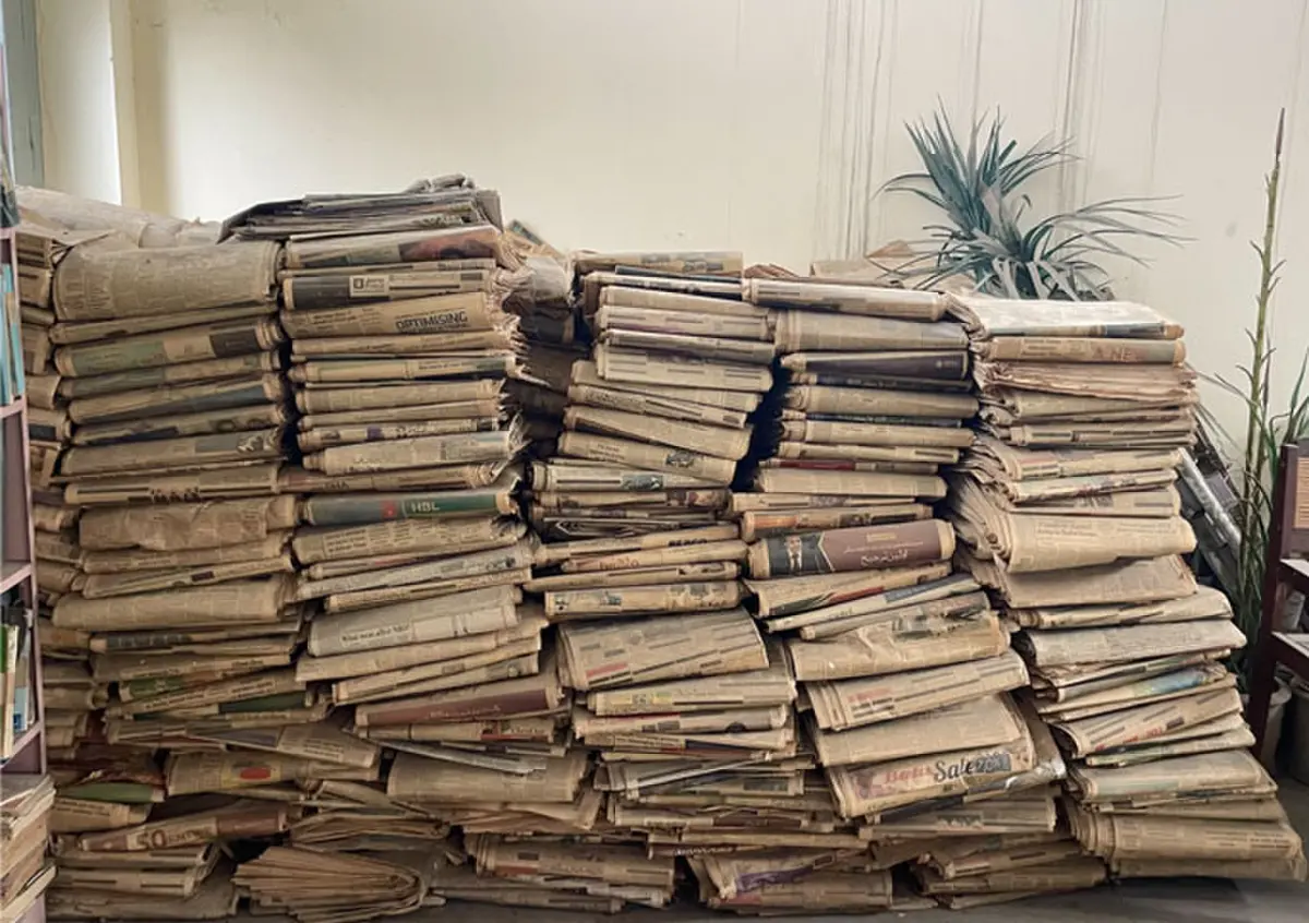   Piles of old newspapers are stacked in a corner of the library.  
