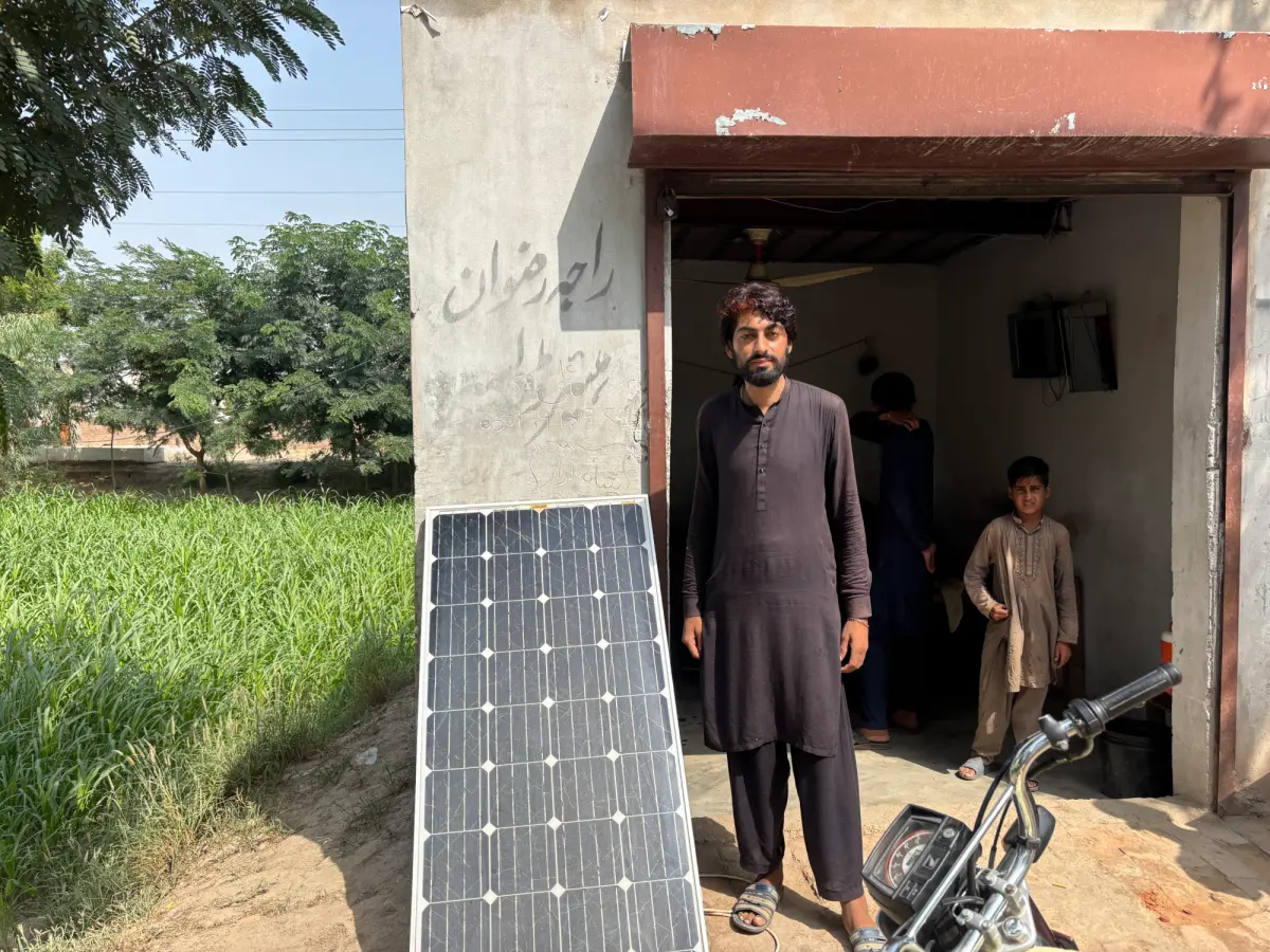 Muhammad Rizwan with his panel that powers the fan in his hairdressing shop