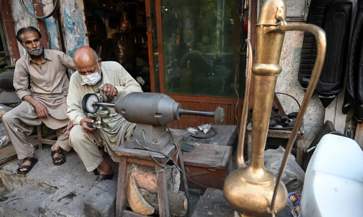 Antique dealer Ahsan Shakeel polishes an artefact outside his shop selling vintage items in Rawalpindi on October 20, 2026. &mdash;AFP