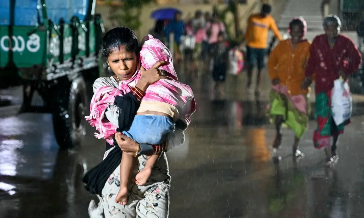 A woman with a child arrives at a relief shelter during rainfall in Andhra Pradesh&rsquo;s Kakinada on October 27, 2026 ahead of cyclone Arnab&rsquo;s expected landfall. &mdash;AFP