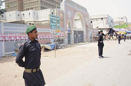 SECURITY men stand guard outside a polling station in Liaquatabad on Monday.—PPI