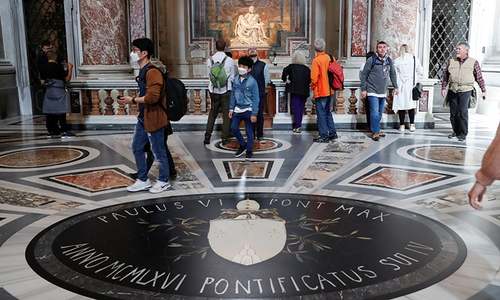 Tourists wearing protective face masks walk next to Michelangelo's Pieta as they visit St. Peter's Basilica on March 6. — Reuters