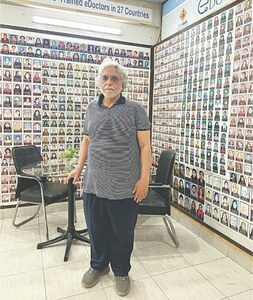 ایجوکاسٹ کے بانی اور چیئرمین عبداللہ بٹ اپنے دفتر میں ایک پینافلیکس کے سامنے کھڑے ہیں جن میں ایک ہزار 500 خواتین ڈاکٹروں کی پروجیکٹ میں شمولیت کی تصاویر موجود ہیں—تصویر: لکھاری